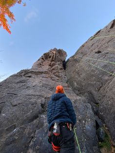 a man climbing up the side of a mountain with a rope attached to his back