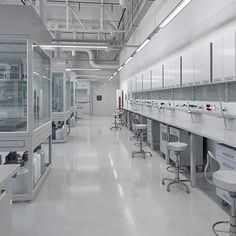 an empty laboratory with lots of white counters and stools in the middle of it