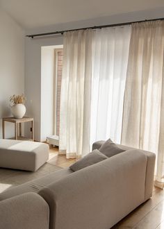 a living room filled with furniture and white curtains