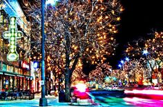 a city street filled with lots of lights and trees covered in christmas lights at night