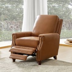 a brown recliner chair sitting on top of a rug in front of a window