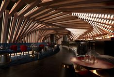 the interior of a restaurant with wooden ceilinging and red chairs, along with tables