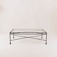 an iron coffee table with glass top against a white background