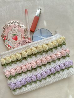 there is a crochet bag with some pens and pencils on it