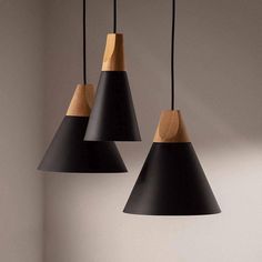 three black and wood pendant lights hanging from a ceiling