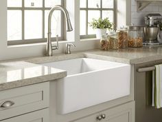 a white kitchen sink sitting under a window next to a faucet and counter top