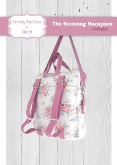 the bookbag backpack sewing pattern is displayed on a white wooden background with pink straps