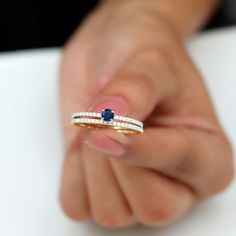 a woman's hand holding a diamond and sapphire ring