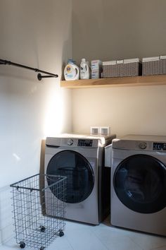 a washer and dryer sitting next to each other in a room with shelves on the wall