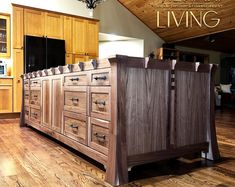 a large kitchen island with wooden cabinets and drawers on the top, in front of a chandelier