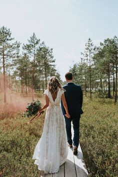 a bride and groom walking down a wooden walkway