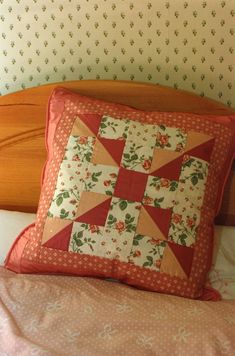 a quilted pillow sitting on top of a bed next to a wooden headboard