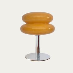 an orange stool sitting on top of a metal base