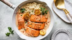 salmon and rice in a skillet with lemons, parsley and garnish