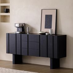 a black cabinet with two cups on it and a coffee maker in front of it