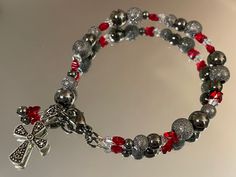 Marcasite Cross Gunmetal Gray/Hematite Beaded Bracelet with sparkling Swarovski crystal beads in red butterflies and clear bicones, shiny and stardust dark gray/grey hematite gunmetal beads and findings, and a marcasite encrusted, Sterling silver cross charm pendant.  This beautiful dark, gray-black and red sparkle bracelet is perfect for elegant Goths, Victorian lovers,  vampire aesthetic, witches, Halloween, and Christmas gifts.  Measures 7.5" long. Handmade in Dayton, Ohio by CinnamonAndSilve Silver Hematite Bracelets With Faceted Beads, Silver Hematite Bracelet With Faceted Beads, Silver Hematite Beaded Stretch Bracelet, Gift Bracelet With Silver Beads And Hematite, Silver Hematite Crystal Bracelet Gift, Vampire Bracelet, Bracelet Gothic, Elegant Goth, Upcycled Vintage Jewelry