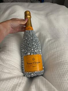 a bottle of champagne being held up on a bed