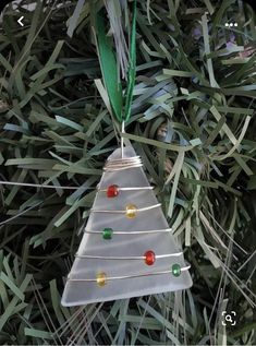 a glass ornament hanging from a tree with green leaves and beads on it