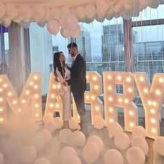 a man and woman standing in front of balloons that spell happy