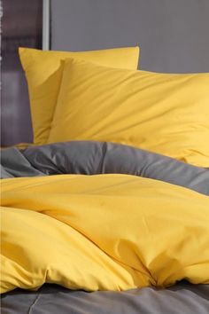 a bed with yellow sheets and pillows on it