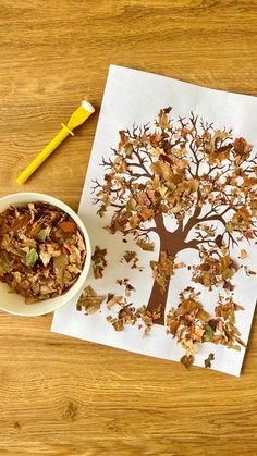 a bowl of cereal next to a paper cut out of a tree with leaves on it