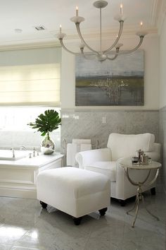 a bathroom with white furniture and a chandelier hanging from the ceiling above it