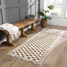 a white and brown rug sitting on top of a wooden floor next to a window