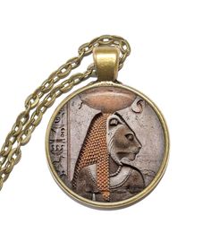 Handmade art pendant necklace featuring the Egyptian goddess Bastet. Bastet, or Bast, was a cat goddess and the patroness of pregnant women. She loved music and dance which made her festival at Bubastis one of the most popular festivals in Egypt. According to records, her festivals had as many as 700,000 attendees. The Egyptians regarded Bastet as the personification of the sun's beneficial powers. Her depictions show her as either a woman with a cat's head or as a cat and people mummified cats Mythological Round Pendant Necklace For Gifts, Mythological Pendant Necklaces As Gifts, Ancient Style Round Pendant Necklace For Gift, Ancient Brass Round Pendant Necklace, Ancient Style Bronze Round Pendant Necklace, Collectible Ankh Amulet Necklace, Handmade Ancient Medallion Necklace, Collectible Ancient Style Pendant Necklace, Bronze Vintage Necklace Gift