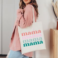 a woman holding a white tote bag with the words mama mamma on it