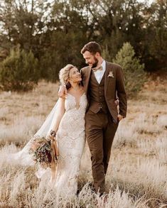 a bride and groom walking through tall grass