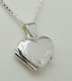 "Photos are precious and here's a lovely way to keep those memories close. Our beautifully worked genuine 925 sterling silver heart picture locket has a hand engraved leaf border along the heart shape itself - so each is a unique work of art. There's also a secure compartment inside to hold two special photos. Our picture locket in genuine sterling silver is small, measuring approx. 5/8\" wide by 3/4\" long - it works as a pendant or as a charm on a bracelet. A lovely piece of jewelry for a youn Classic Heart-shaped Sterling Silver Locket Necklace, Classic Heart Shaped Sterling Silver Locket Necklace, Classic Sterling Silver Heart Locket Necklace, Silver Sterling Silver Heart Pendant Locket Necklace, Sterling Silver Heart Locket Necklace For Memorial, Silver Sterling Double Heart Locket Necklace, Silver Sterling Silver Locket Necklace With Heart Charm, Silver Heart Necklace With Round Pendant For Keepsake, Silver Locket Necklace For Mother's Day Anniversary