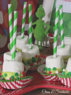 there are many green and white striped straws in the cupcakes on the table