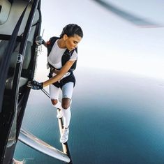 a woman in white shirt and black shorts standing on the edge of an airplane window