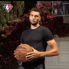 a man holding a basketball in his right hand and wearing a black shirt with the word moon written on it