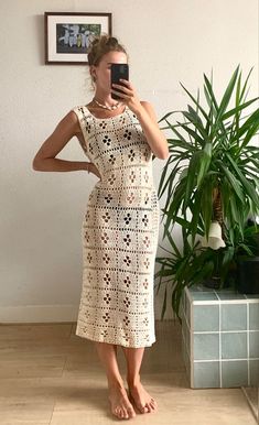 a woman taking a selfie in front of a mirror wearing a crocheted dress