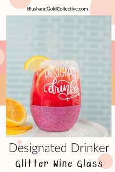 a pink glitter wine glass with the words designated drinker written on it and an orange slice