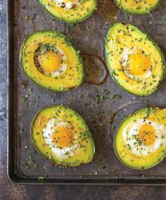 baked eggs in avocado halves on a baking sheet