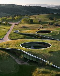 an aerial view of a winding road in the middle of a green field with hills and trees