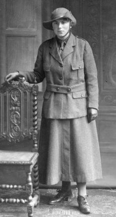 an old black and white photo of a man in uniform standing next to a chair