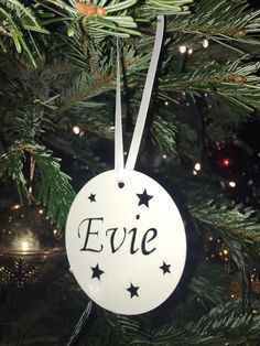 a white ornament hanging from a christmas tree with the word eve written on it