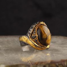 Silver and gold-plated men's ring 925 sterling silver brown Tigers Eye Stone handmade high quality Product Approximate 17 to 19 gr. Handling time : 2 business days The ring is made of 925 sterling silver.  You can contact us for different color and style options. Your order is sent as a gift package in an REVIST Special Gift Box.*  If you have a special note for your gift shipments, you can let us know during your order.*  A silver polishing cloth will be delivered to you in your cargo as a gift from our company, so you can easily take care of your silver ring.  You can extend the life of your silver accessory by avoiding soap, deodorant, sweat and water.* You can find out your ring size from the jeweler for free.Goods delivery time varies between 9-15 working days depending on the region Tigers Eye Gem, Tigers Eye Stone, Unique Mens Rings, Brown Tiger Eye, Tiger Eye Jewelry, Natural Gemstone Ring, Mens Silver Rings, Mens Ring, Tiger Eye Stone