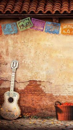 an acoustic guitar sitting on the ground next to a wall with colorful tiles hanging from it