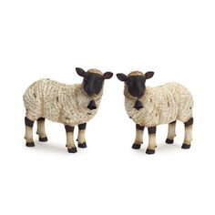 two toy sheep standing next to each other on a white surface with one looking at the camera