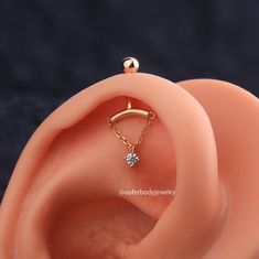 an ear piercing with a single diamond in it's middle, on top of a black background