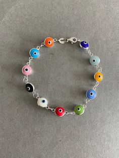 Multi-Color Evil Eye Bracelet Tiny Evil Eye charm, Greek Eye Bracelet, Turkish Eye Bracelet - Sterling Silver ★ Quantity : One Piece ★ Type : A / B / C / D / E / F / G ★ Materials : Sterling Silver ★ Each Evil Eye Size : 10mm ★ Length : 7.5 inches ★ Suitable for delicate and sensitive skins. ★ All purchases come in a small gift box perfect for gift giving. Multiple items will be boxed together. If you need extra boxes for gifting....just let us know! Evil Eye Types, Multicolor Round Jewelry With Lobster Clasp, Nickel-free Multicolor Charm Bracelet For Jewelry Making, Rainbow Charms Bracelet As A Gift, Multicolor Round Bracelets As Gift, Multicolor Round Evil Eye Jewelry, Multicolor Round Bracelets For Gifts, Nickel Free Multicolor Metal Bracelets, Multicolor Nickel Free Metal Bracelets