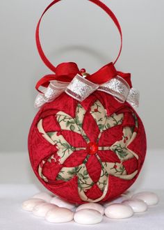 a red ornament hanging from a ribbon on top of some white rocks and pebbles