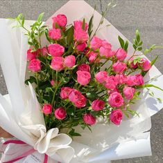 a bouquet of pink roses is wrapped in white paper and ready to be picked up