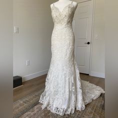 a wedding dress is displayed on a mannequin in front of a white door