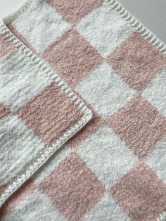 two pink and white checkered rugs on top of each other, one is folded up