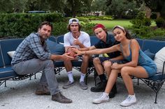 a group of people sitting on top of a blue bench next to eachother